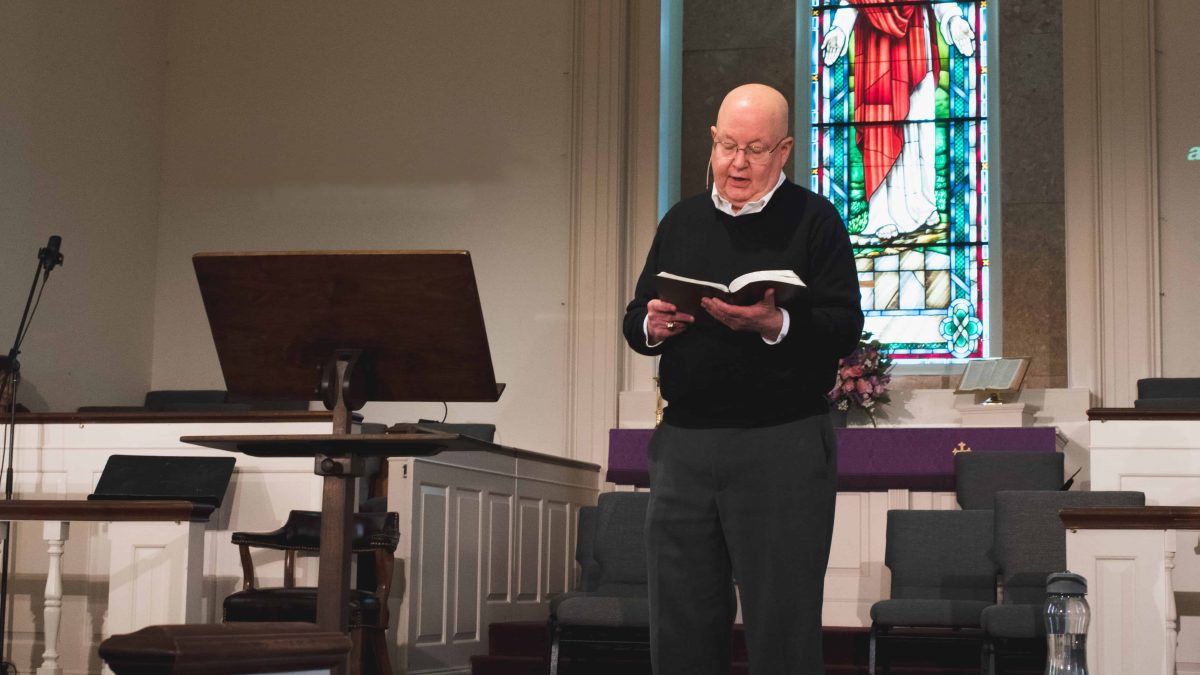 Tommy McDearis reading scripture during the worship service